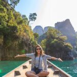 Asian woman relishing a serene boat journey through the lush karst landscape of Thailand's Khlong Sok.
