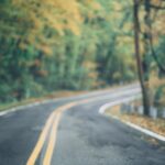A scenic winding road through a vibrant autumn forest in Long Pond, PA.