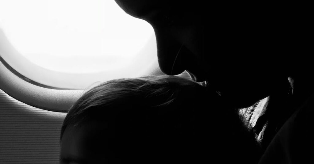 Silhouette of a mother and child gazing out an airplane window during flight.