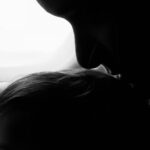 Silhouette of a mother and child gazing out an airplane window during flight.