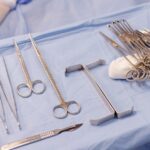 A set of surgical instruments carefully arranged on a blue drape during an operation.