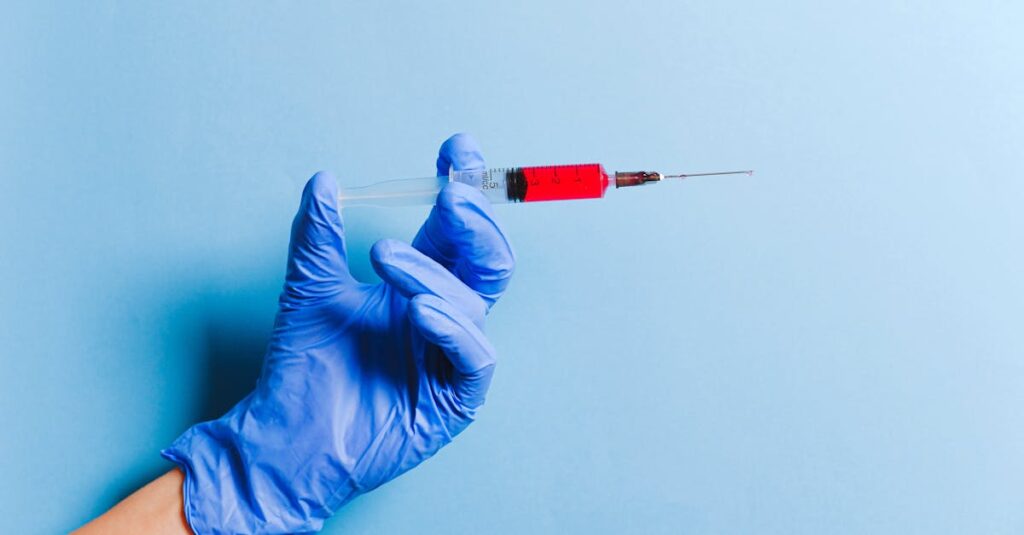 Close-up of a gloved hand holding a syringe with red fluid against a blue background, symbolizing healthcare and medicine.