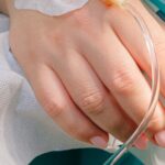 Close-up of a patient's hand receiving intravenous therapy in a hospital setting.