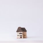 Minimalistic photo of a handmade clay miniature house placed on a clean white background.