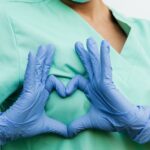 Medical professional forming a heart shape with blue gloves. Symbol of care and compassion.