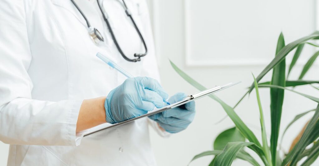 A healthcare professional wearing gloves takes notes on a clipboard with a stethoscope around their neck.