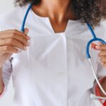 A female doctor holds a stethoscope, focusing on healthcare professionalism.
