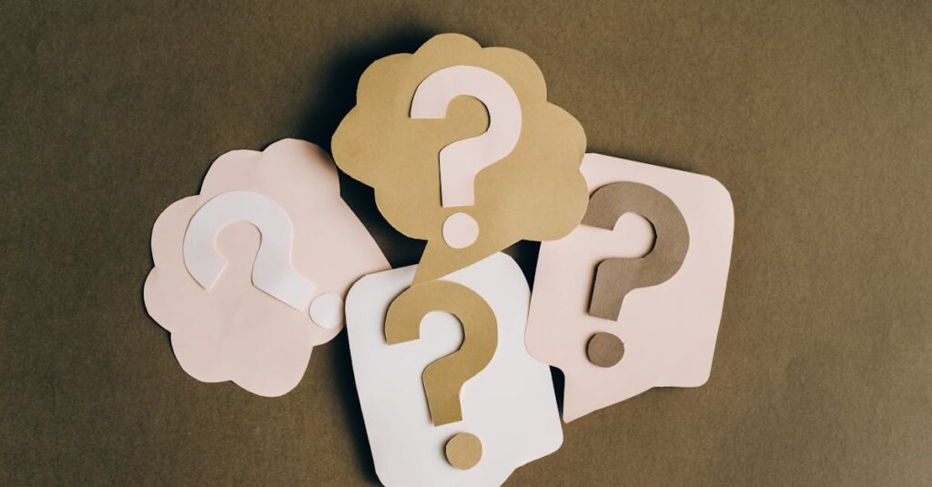 Four paper cutouts of question marks in beige and white on a brown surface, symbolizing inquiry and curiosity.
