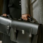 Group of adults holding sleek leather briefcases in formal business attire, emphasizing corporate professionalism.