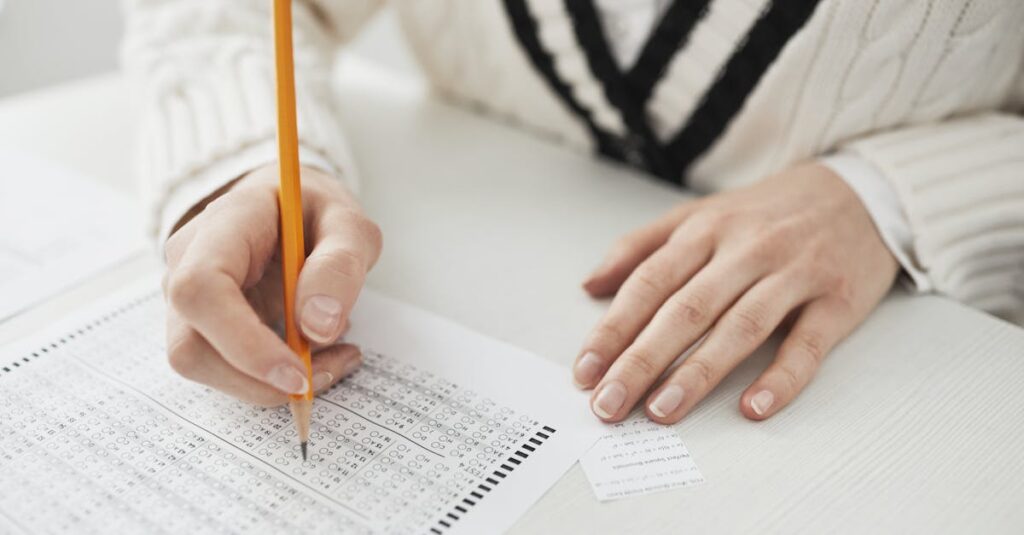 A student writing answers on a multiple-choice exam sheet at a desk.