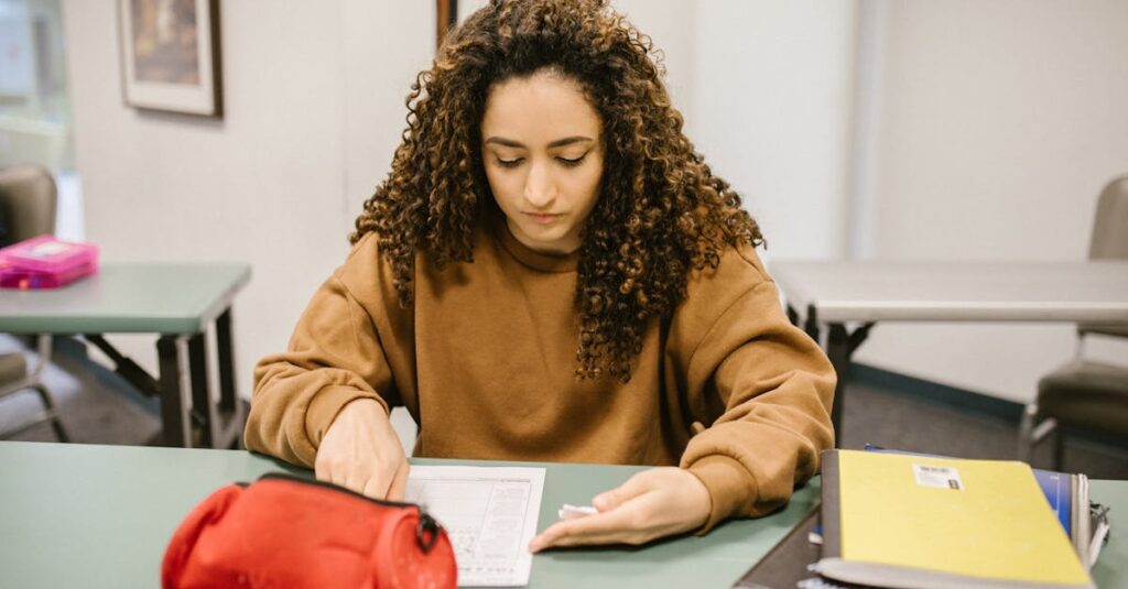Young woman studying for an exam in a college classroom with books and notes.
