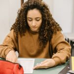 Young woman studying for an exam in a college classroom with books and notes.