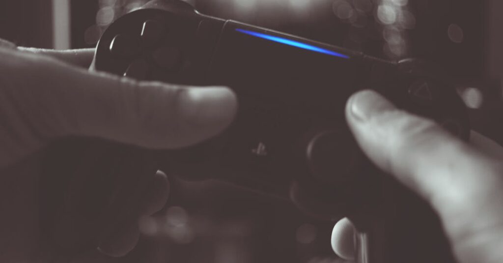 Close-up of hands gripping a gaming controller in dim light, emphasizing electronic entertainment.