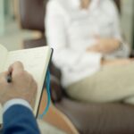 Therapist writing notes during a counseling session with a client.