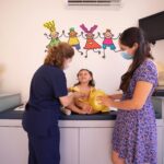 Doctor checks a young child at a pediatric clinic with a parent present.