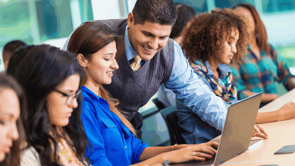 Hispanic professor helping student in busy college classroom View more by SDI Productions fro