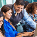 Hispanic professor helping student in busy college classroom View more by SDI Productions fro