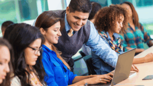 Hispanic professor helping student in busy college classroom View more by SDI Productions fro
